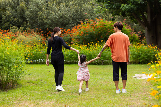 Mother and Father holding and jump up daughter in the air at spring park, moment of family bonding and togetherness. outdoor activitie. Asian Family with father mother daughter and grandfather