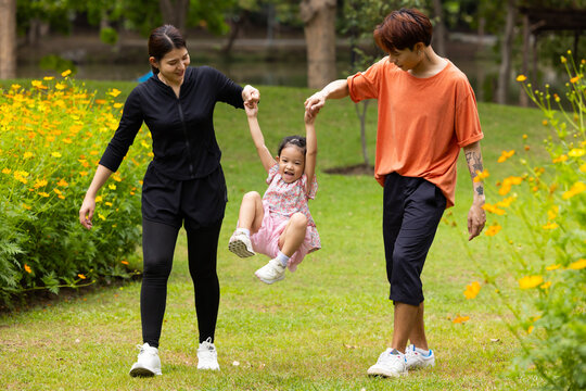 Mother and Father holding and jump up daughter in the air at spring park, moment of family bonding and togetherness. outdoor activitie. Asian Family with father mother daughter and grandfather