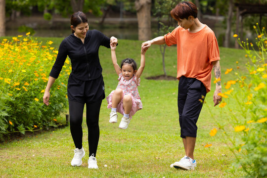 Mother and Father holding and jump up daughter in the air at spring park, moment of family bonding and togetherness. outdoor activitie. Asian Family with father mother daughter and grandfather