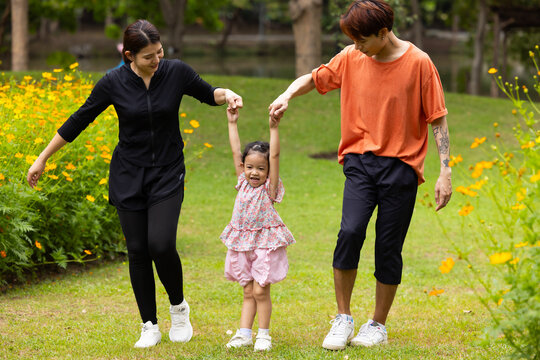 Mother and Father holding and jump up daughter in the air at spring park, moment of family bonding and togetherness. outdoor activitie. Asian Family with father mother daughter and grandfather