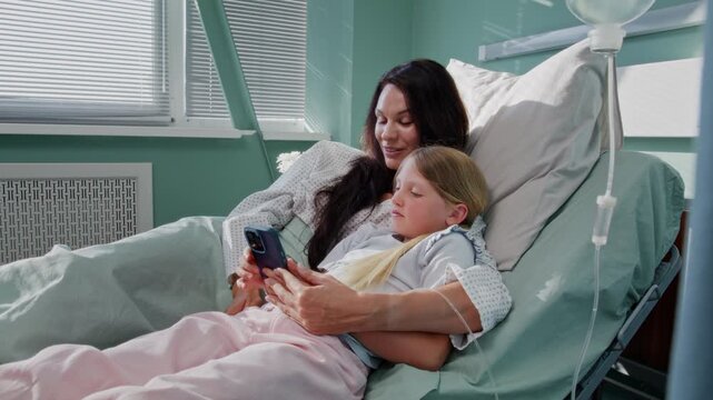 Mother and daughter share smartphone during hospital recovery