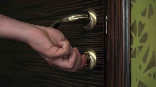 Close-up of a hand unlocking the door latch and opening the door