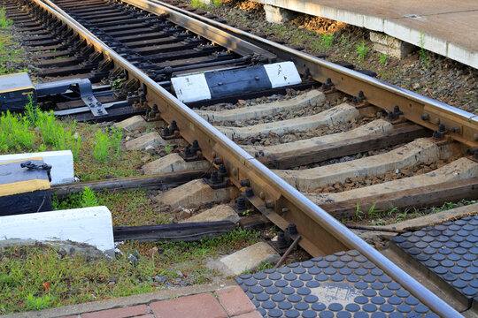 Railway track switch mechanism with steel rails, train turnout system with wooden and concrete sleepers near platform