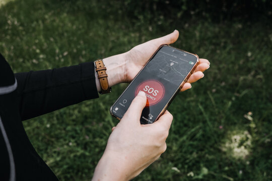 Woman holds smartphone displaying interface with map and active emergency button. Personal safety app, SOS emergency button, panic button smartphone, Safety check-in app.