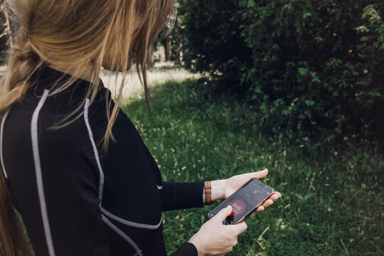 Woman holds smartphone displaying emergency SOS alert screen outdoors. Women personal safety app, emergency sos button, urban security device.