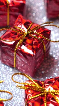 Red present boxes on silver background. Rotate. Christmas and New Year decoration. Winter holidays. Vertical footage