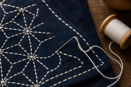 Sashiko embroidery in progress with needle and thread on indigo fabric