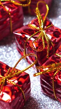 Red present boxes on silver background. Rotate. Christmas and New Year decoration. Winter holidays. Vertical footage