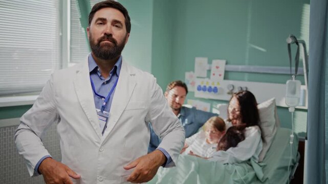 Confident doctor watches supportive family visit in hospital ward