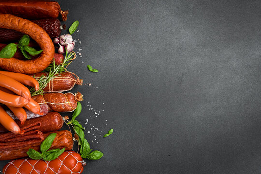 Various kind types of salami and sausages on a dark table. Free space for text.