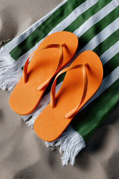 Orange flip flop beach towel sand summer footwear striped casual vacation outdoor relaxation. Bright orange flip flop green striped towel sand
