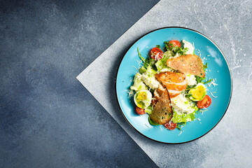 Obraz premium Fresh vegetable salad with chicken fillet and egg. Traditional Caesar salad. In a blue plate.