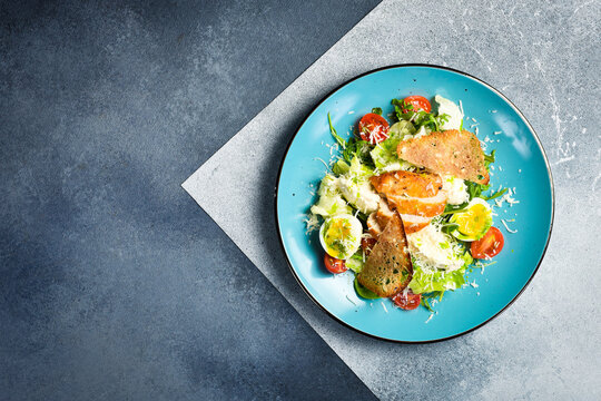 Fresh vegetable salad with chicken fillet and egg. Traditional Caesar salad. In a blue plate.