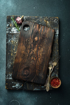 Wooden kitchen tray. Kitchen textured cutting board. Kitchen decorative accessories. On a dark background. Top view. Free space for text.