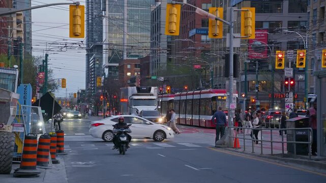 Urban intersection in Toronto with pedestrians crossing street, busy traffic, tramway commuting, showing city life, modern architecture, public transportation system. 02,02,2026, Toronto, Canada, 