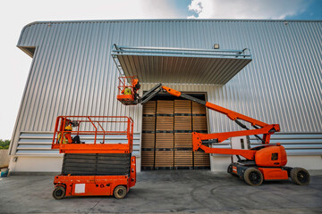 Fototapeta premium Workers are working on the Orange articulate boom lift or telescopic boom lifts and bucket crane mounted on truck for working at heights and articulating boom