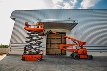 Workers are working on the Orange articulate boom lift or telescopic boom lifts and bucket crane mounted on truck for working at heights and articulating boom © chitsanupong