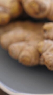 Roots of ginger rotating on plate. Vertical footage