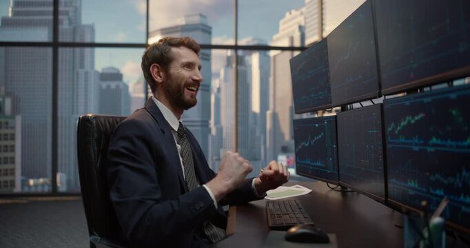 Portrait of Stockbroker Reviews Trading Data on Screen Desk Setup, Smiling with Victory and Success as He Monitors Financial Charts, Investment Portfolios Capital show Growth in Office.