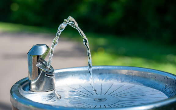 Outdoor drinking fountain with streaming water in public park. Hydration and Public Health Infrastructure