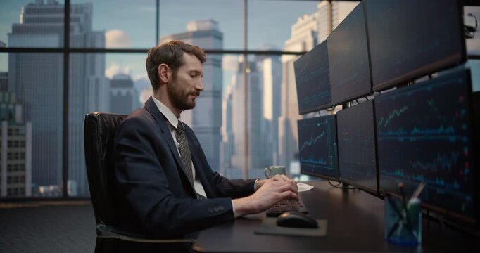 Portrait of Stockbroker Reviews Trading Data on Screen Desk Setup, Smiling with Victory and Success as He Monitors Financial Charts, Investment Portfolios Capital show Growth in Office.