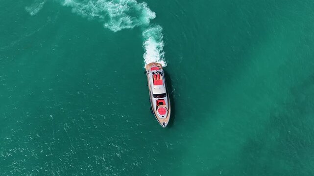 Motorboat enters marina while luxury yacht waits beside boat dock. Sea reflects bright summer sun. Yacht, boat, sea and luxury invite relaxing boating, travel and unforgettable vacation