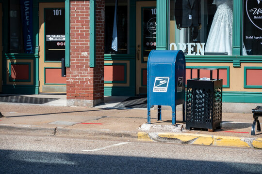 CHIPPEWA FALLS, WI, USA - JULY 12, 2026: Blue USPS mailbox on a downtown sidewalk in front of a boutique. Editorial Use Only.
