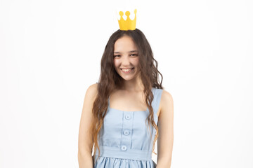 Smiling young girl wearing golden crown looking directly at camera in the studio