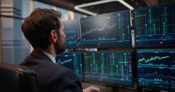 Arc Shot Portrait of Male Stockbroker Analyzes Market Data on Multiple Monitors at His Desk, Studying Financial Charts and Graphs for Investment Strategy and Capital Growth