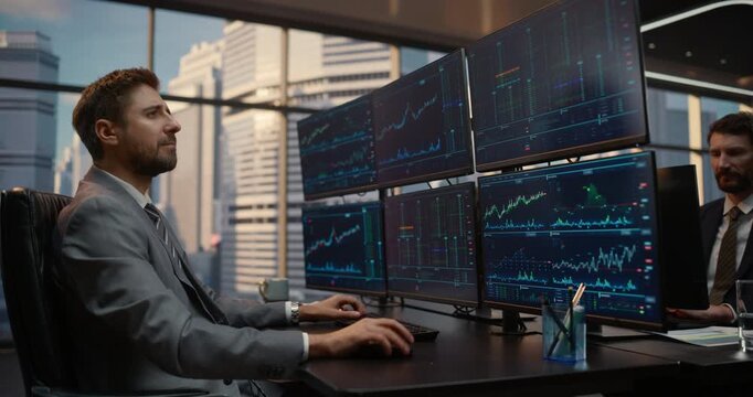 Two Male Traders Work in Financial Office, Examining Stock Market Charts on monitor Desk Setup to Assess Investment Risk and Optimize Portfolio Returns. Arc Portrait of Asset Manager