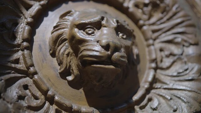 Carved wooden lion medallion with shifting focus, warm directional highlights, rich relief detail, ornate scrollwork, and subtle viewpoint movement, with lion, carving, wood, relief detail