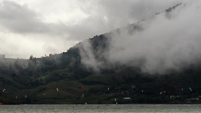 colorful kitesurfing kites over lake calima with cloudy mountain background