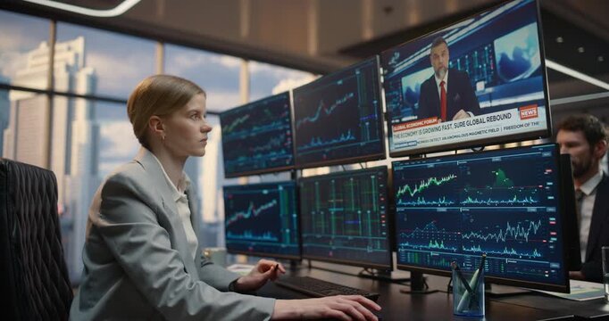 Female Stockbroker Trader Watches Financial TV News Channel Broadcast While Analyzing Stock Exchange Data on a Multi monitor Desk Setup, Reviewing Equity Charts and Market Analytics for Investments