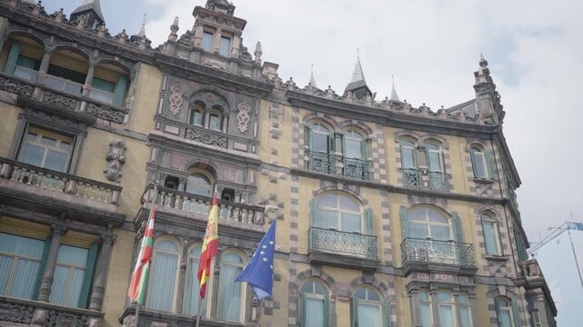 Ornate historic building facade with fluttering flags in overcast daylight