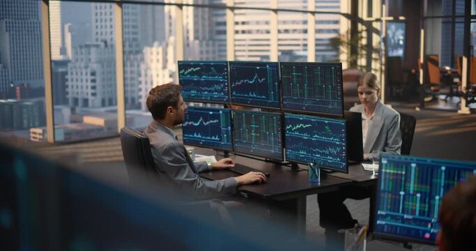 Team of Stockbrokers Work at Desks With Multi-monitor Setups Displaying Stock Exchange Feeds, Tracking Market Charts, Financial Data and Trading Analytics to Drive Investment Growth.