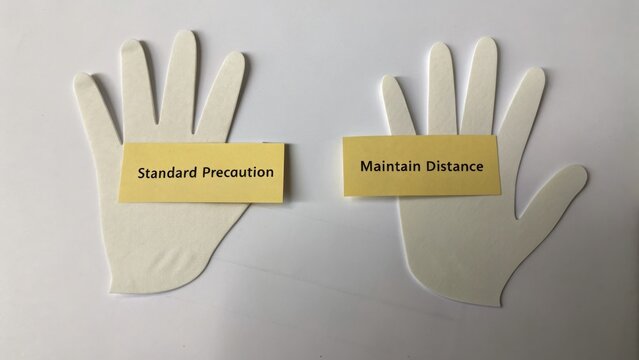 White Paper Hands with Labels on Standard Precaution and Maintain Distance for Safety and Health Guidelines Display