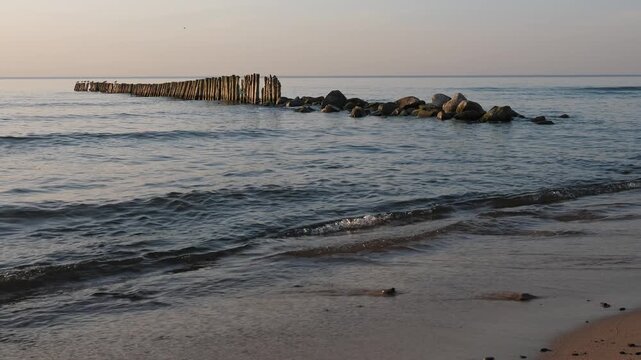 Sunset at Baltic sea, seascape with wooden breakwaters and seagulls, nobody