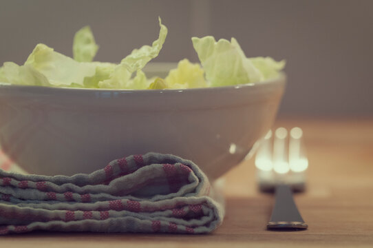 Close-up of a Bowl of iceberg lettuce and fork on a folded tea towel on a table