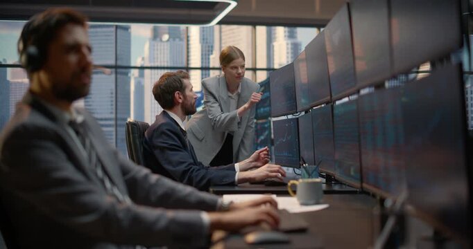 Financial Team Analyzes Stock Exchange Data at a Trading Desk: a Male Broker in Headset Talks While Two Colleagues Point at Investment Analytics, Financial Charts, Capital Growth on Computer Screens