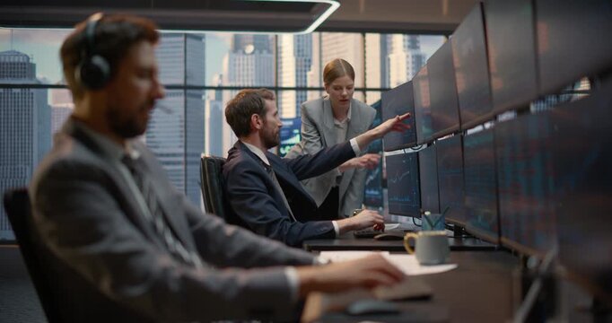 Financial Team Reviews Stock Exchange Data at a Trading Desk: a Female Broker Points at Investment Analytics on Screen While Discussing Market Trends and Capital Growth With Two Male Trader Colleagues