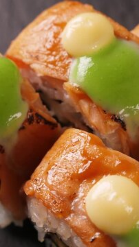 Sushi rolls with salmon rotating, closeup. Japanese cuisine. Vertical footage