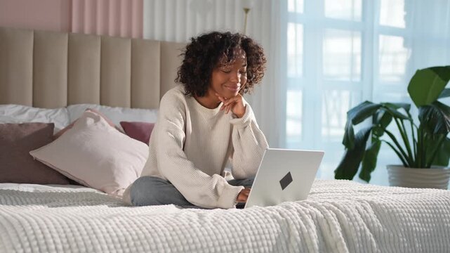 African American girl using laptop in bed at home office typing chatting reading writing email. Young black woman having virtual meeting online chat video call conference. Work learning from home