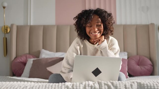 African American girl using laptop in bed at home office typing chatting reading writing email. Young black woman having virtual meeting online chat video call conference. Work learning from home