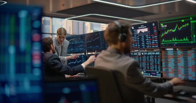 Financial Team Analyzes Stock Exchange Data and Investment Analytics at a Trading Desk; a Headset Trader Monitors Capital Growth Charts on Computer Screens as Two Colleagues Talk About Market Strategy