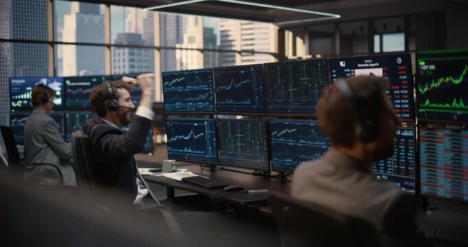 Broker in Headset Studies S&p 500 Investment Data and Capital Growth Analytics at a Trading Desk, While a Team of Financial Analysts Monitor Stock Exchange Charts and Portfolio Performance