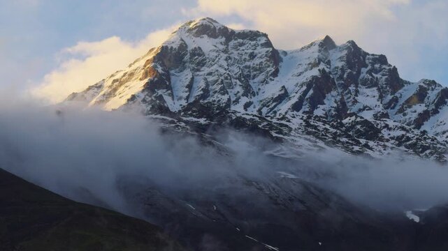 4K shot of snow covered Himalayan mountain peak surrounded by clouds after fresh snowfall during the winter season as seen from Sissu village in Lahaul and Spiti district, Himachal Pradesh, India. 