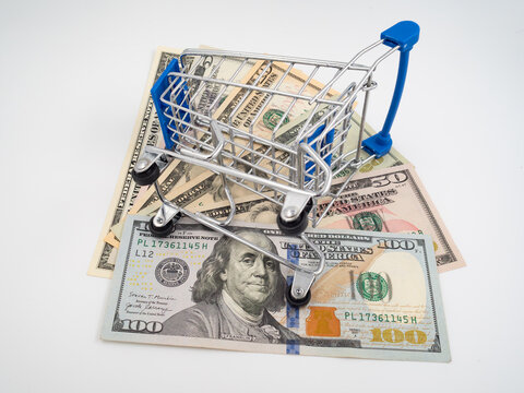 Shopping cart with US dollar banknotes isolated on white background