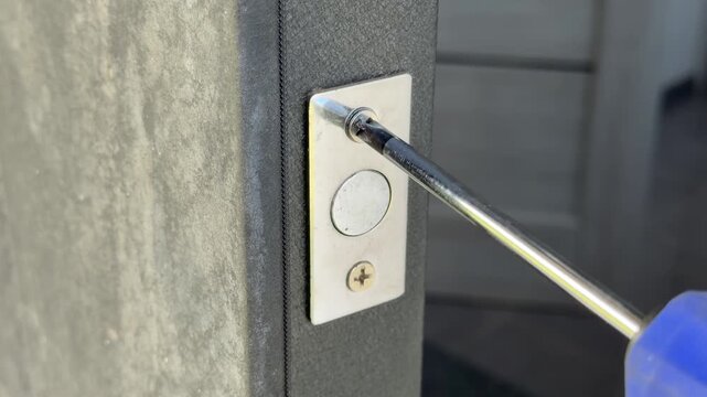 Handyman unscrewing a door latch plate