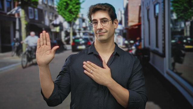 Man raising palm and placing other hand on chest in a pledge gesture on a busy street lined with shops and bicycles; sincerity honor.