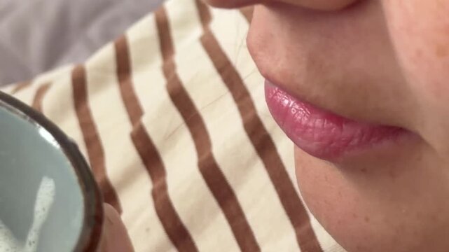 Close up of a woman drinking foamy milk from a mug